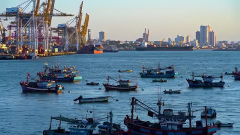 a scenic view of a busy waterfront with fishing boats and cargo ships under the glow of sunset, capturing the vibrancy of maritime industry and city skyline