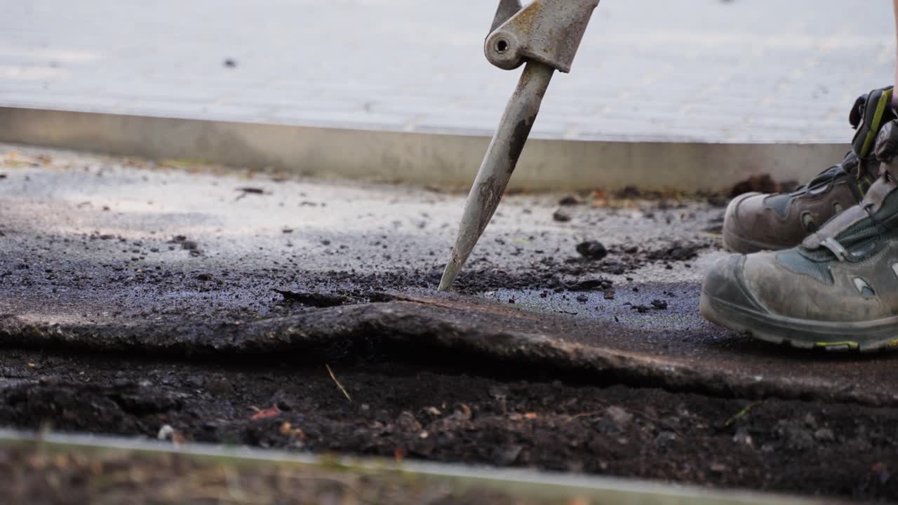 крупным планом снимок строителей, разбивающих гудрон с помощью перфоратора