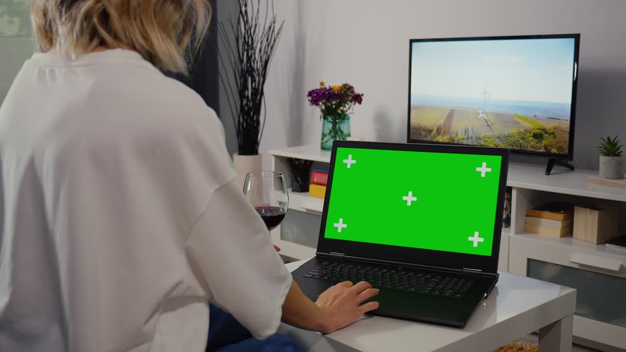 la mujer hace compras en línea en una computadora portátil con pantalla verde.