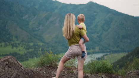 La-Madre-Sostiene-Al-Niño-Y-Señala-El-Río-En-El-Valle-De-La-Montaña.