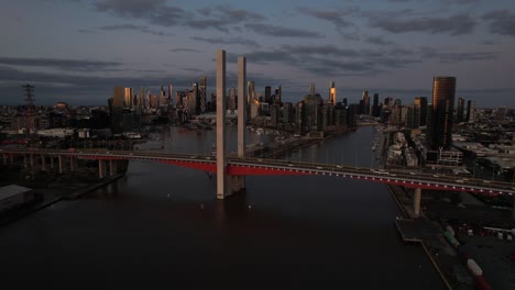 Aerial-car-crossing-Bolte-bridge-Melbourne-city-skyline-dusk,-Australia