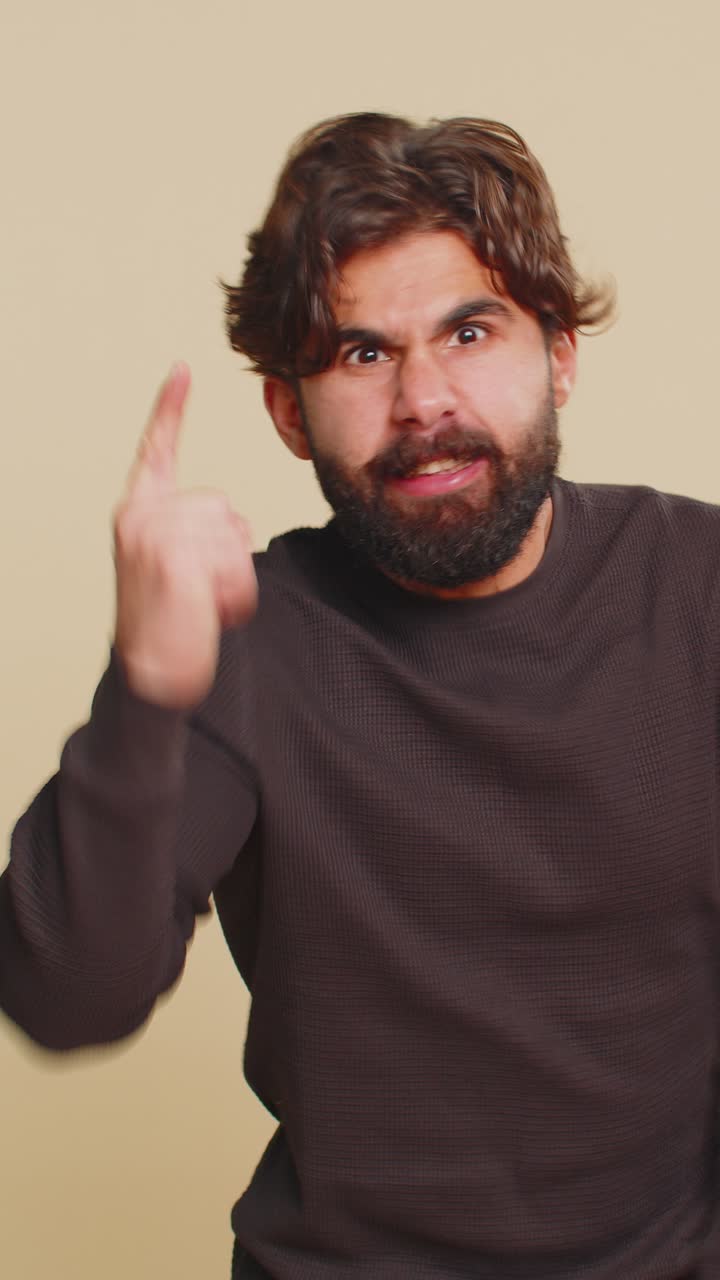 Displeased young hindu man gesturing hands with irritation and displeasure against beige background