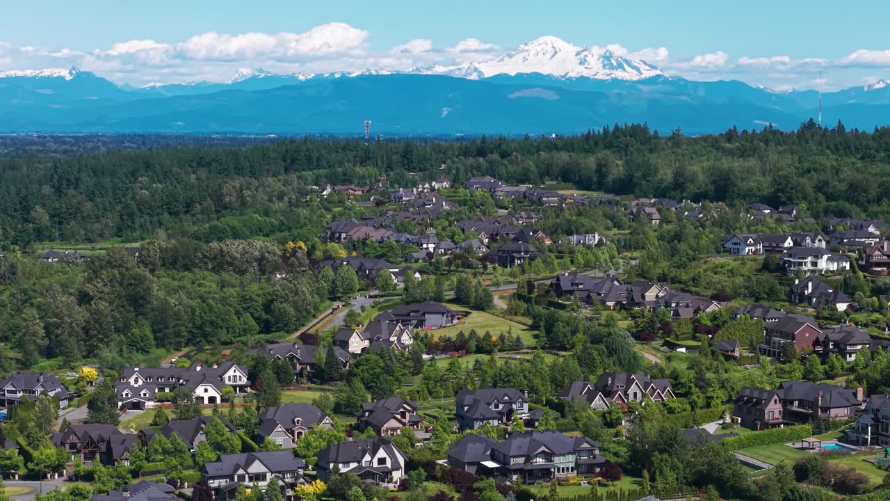 A scenic shot of a luxury suburban neighborhood surrounded by lush green trees in Langley Township, British Columbia, Canada with views of Mt Baker under a beautiful blue sky