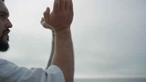 Athletic-man-making-hands-exercises-practicing-karate-on-nature-close-up.