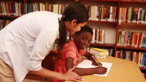 Teacher-helping-pupil-and-smiling-at-camera