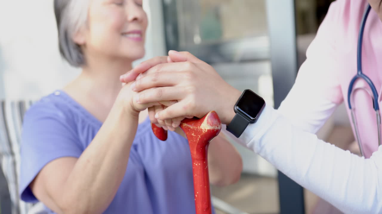 Helping senior asian woman with walking cane, caregiver providing support at home