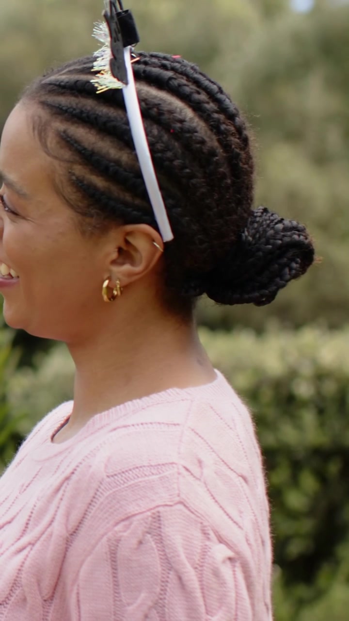 Video verticale: Braccio di un aiutante che mette una fascia per capelli a una donna in giardino, acconciando uno chignon, con orecchini a cerchio d'oro.