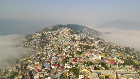 colorida ciudad en la cima de la colina cubierta de niebla