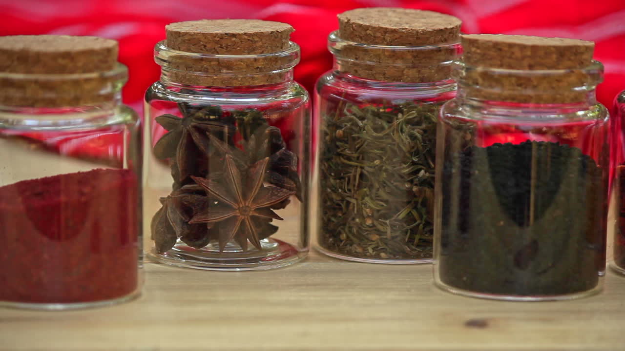 selección de tarros con especias secas dispuestas en fila sobre una mesa de madera