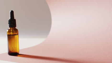 close up of dropper serum bottle on pink background with copy space