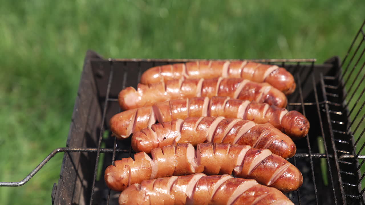 Tasty sausages on a grill grate. Sausage roasting over a barbecue fire in a hot day during the summer vacation. Cooking food for picnic.
