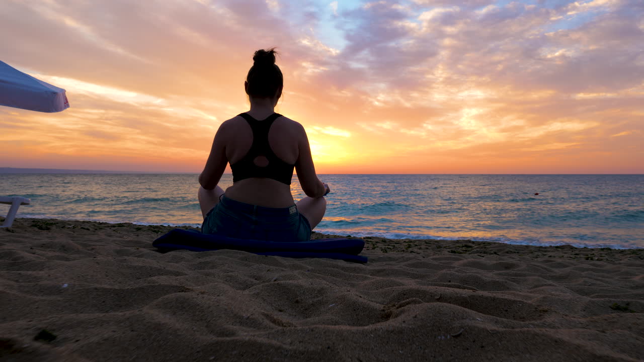 Woman in silhouette on the beach practicing yoga