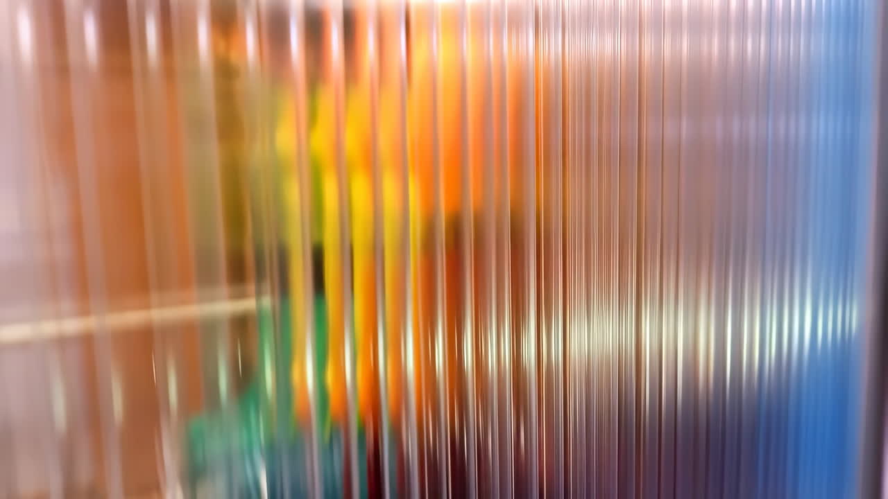 Abstract view through translucent ribbed panels with blurred colors