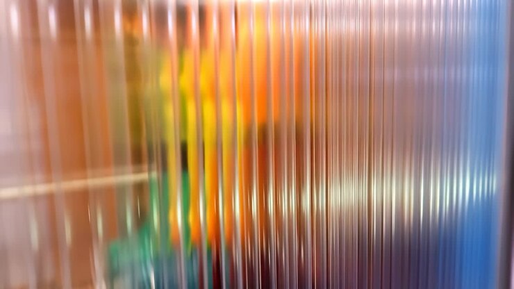 Abstract view through translucent ribbed panels with blurred colors
