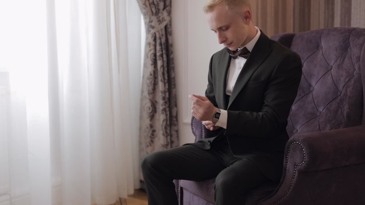 한 남자 가 슈트 와 파이타이 를 입고 결혼식 날 을 준비 하고 있다