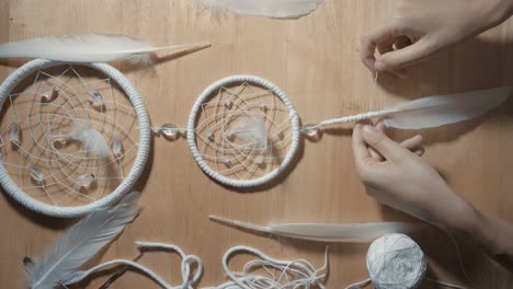 female hands creating dream catcher closeup, vertical angle