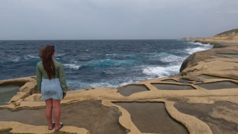 Frau-Beobachtet-Das-Meer,-Während-Sie-Auf-Den-Salzpfannen-In-Malta-Steht---Zeitlupe