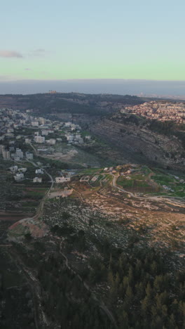 the mountainous area of ramot neighborhood in jerusalem, israel on the right and beit iksa, the palestinian village on the left over the kidron valley, israel - vertical video