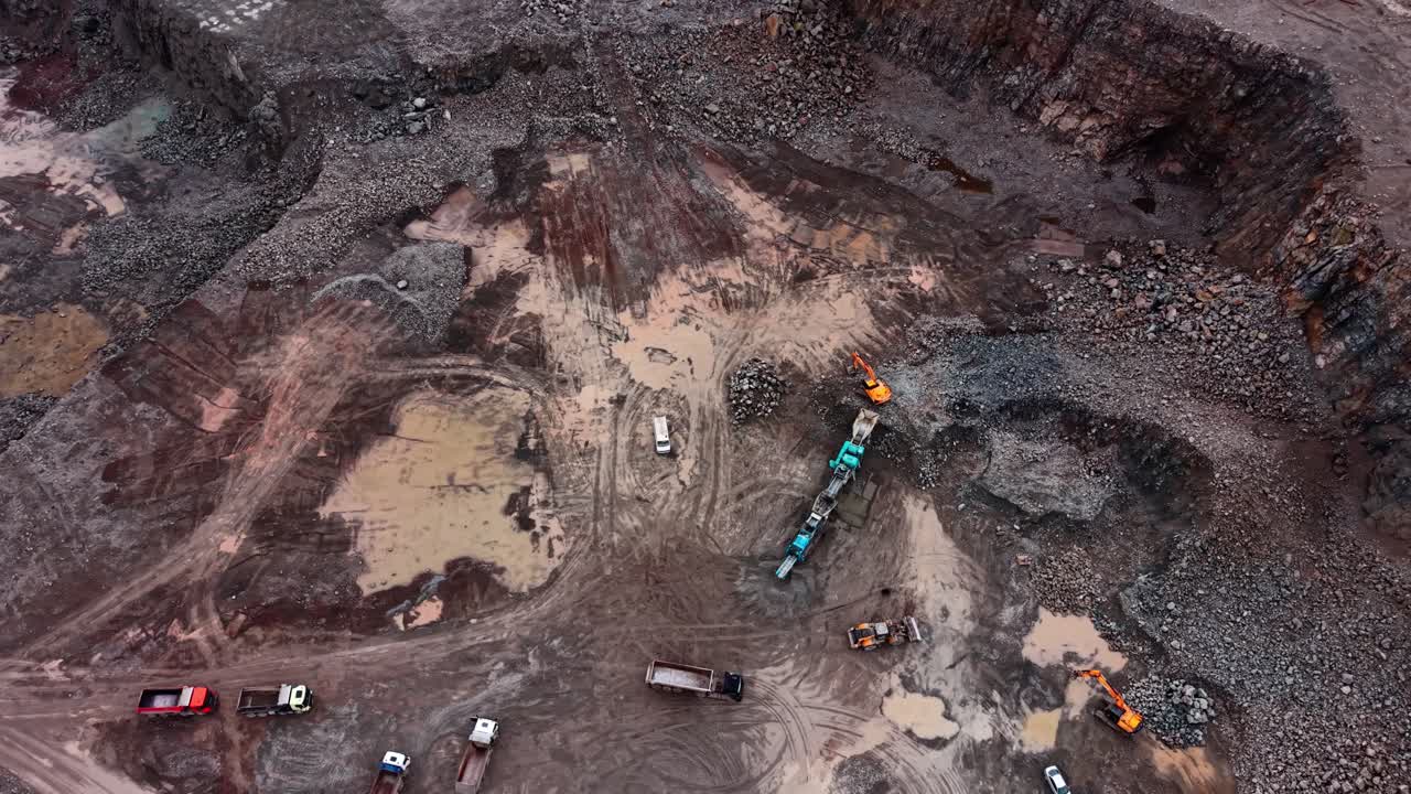 Heavy machinery works in granite quarry site on a cloudy day