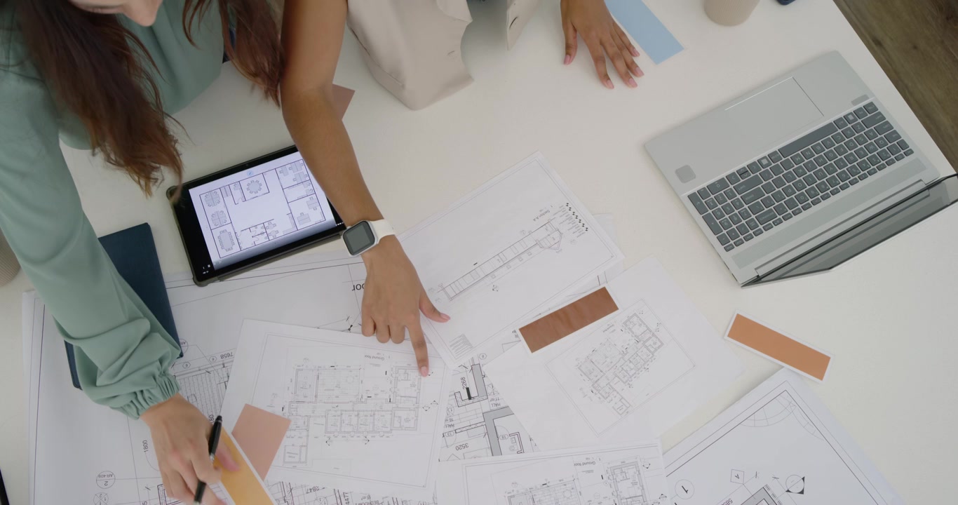 Colleghe diverse che iniziano con piani stampati e tablet, posizionando campioni per la revisione del design