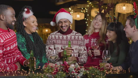 Sliding-Shot-of-Group-of-Friends-Socialising-In-a-Bar-During-Christmas-Celebrations