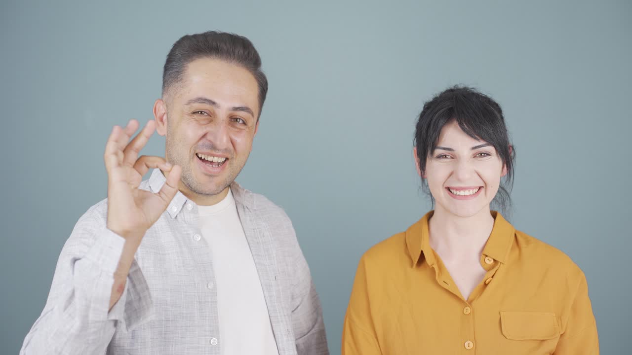 una pareja haciendo un gesto positivo a la cámara.