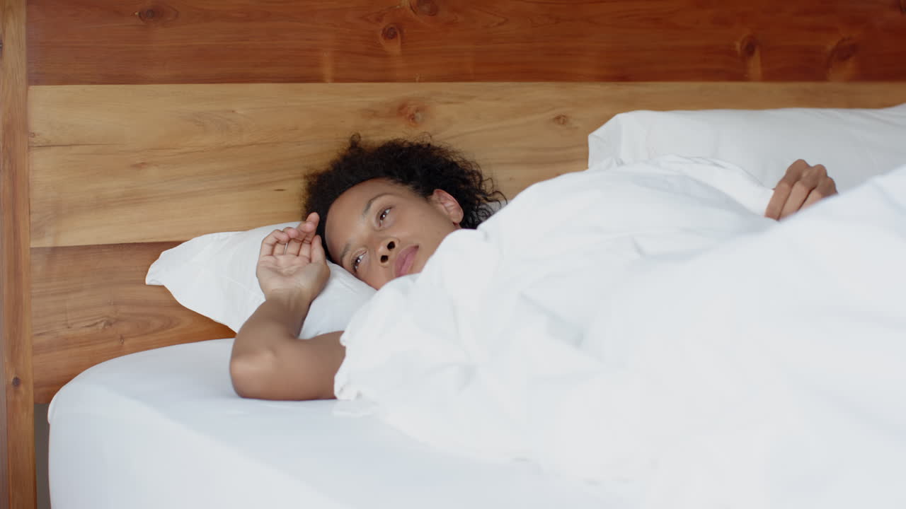 Donna che si stira a letto, svegliandosi riposata e pronta per la giornata, a casa