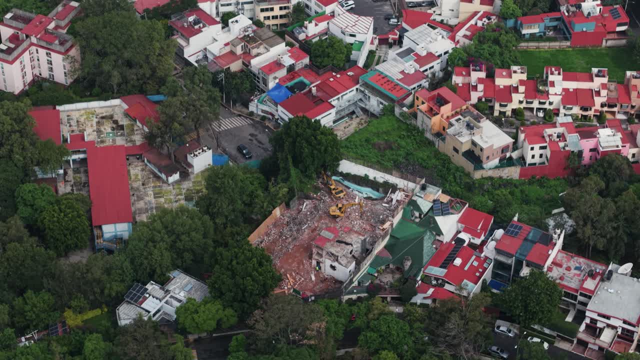 Drone footage of a backhoe at work on a demolished house