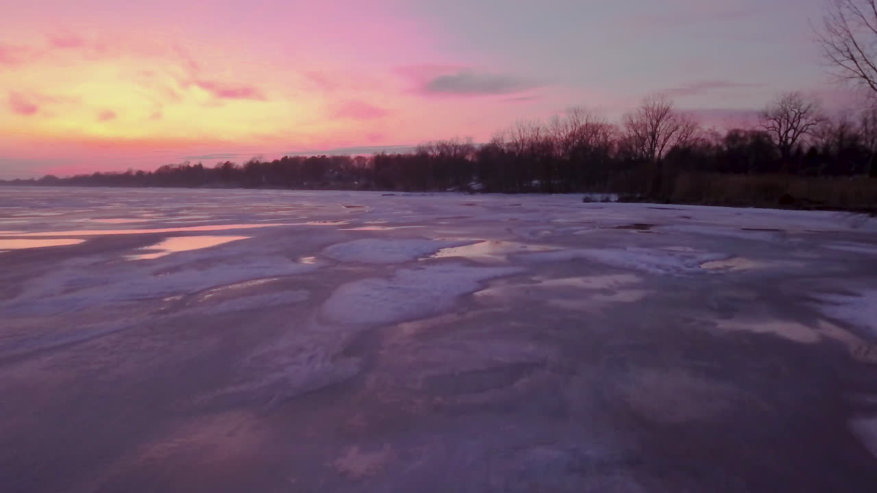 vibrante puesta de sol rosa y naranja sobre un lago costero congelado en el sur de ontario, canadá