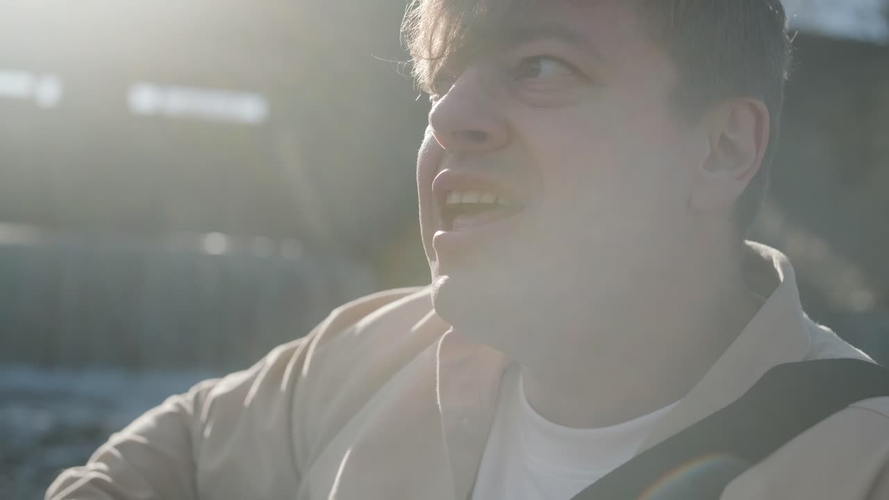 바위의 배경에 산의 강변에 앉아 기타를 연주하는 젊은이. 자유의 개념, 휴식 장소.