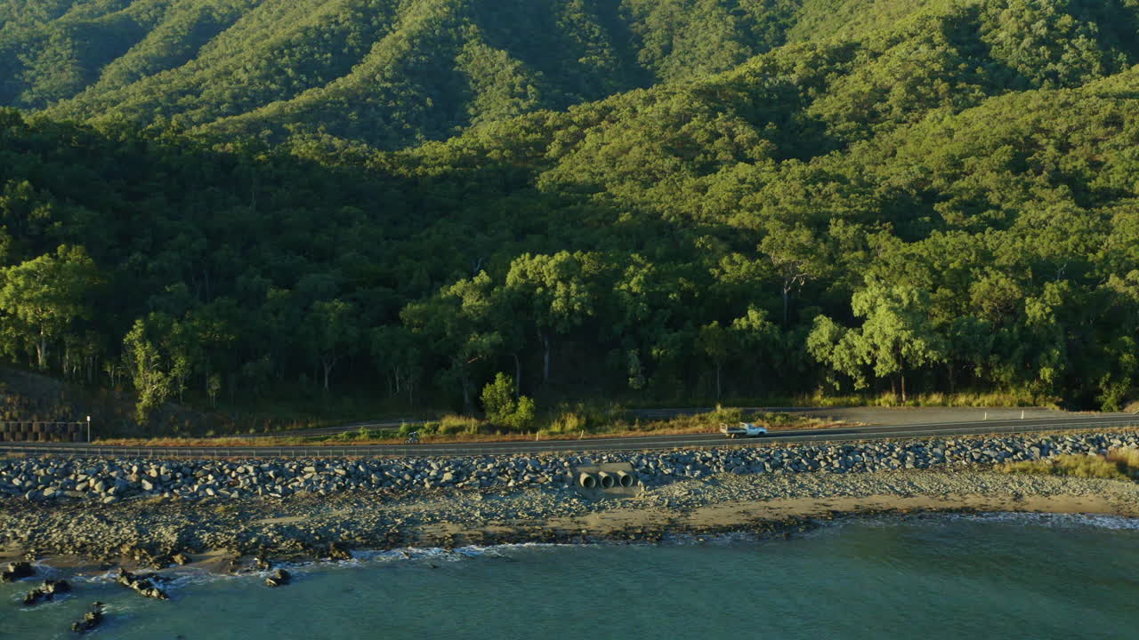 호주, 4k의 경치 좋은 해변가 해안 도로에서 자전거를 타는 프로 운동 선수의 공중 드론 보기를 밀어 넣습니다.