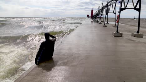 Surfer-sitting-on-Grand-Haven,-Michigan-pier-on-Lake-Michigan