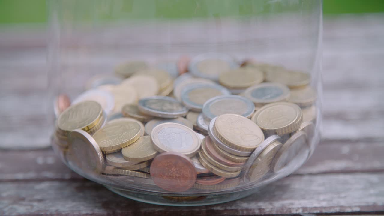inclinación hacia abajo de un gran vaso que contiene varias monedas de euro