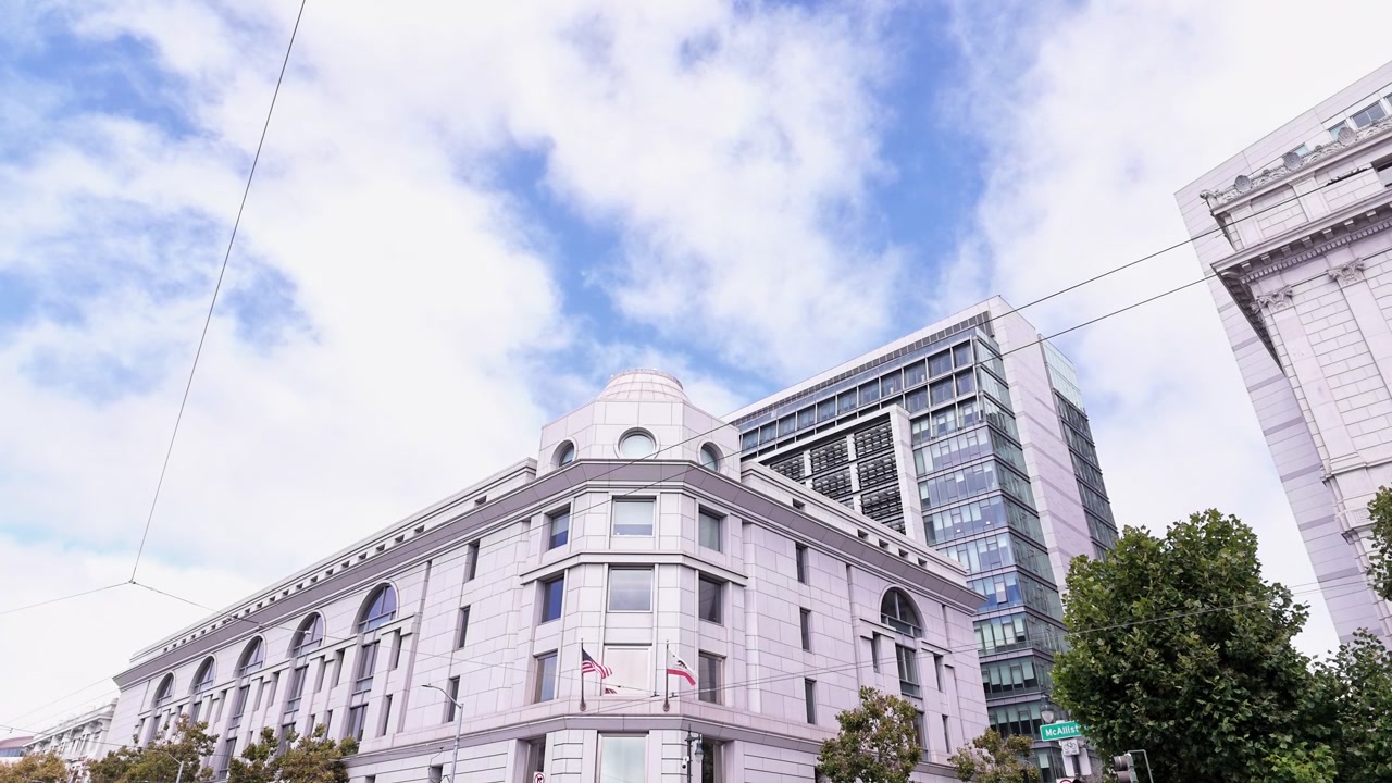 Vista en ángulo contrapicado del Edificio Federal y Tribunal de los Estados Unidos Phillip Burton en el centro de San Francisco, California, con nubes moviéndose a través del cielo azul en un día brillante