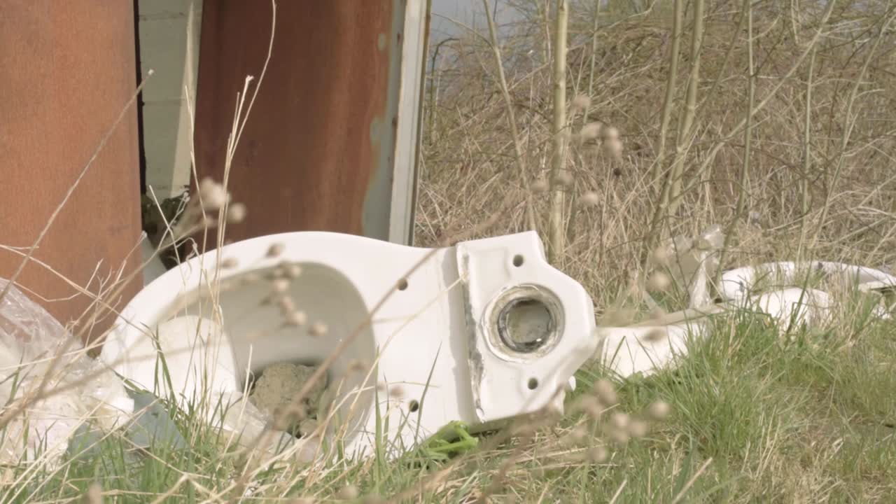 버려진 화장실과 쓰레기가 밖에 방치된 틸팅 미디엄 샷