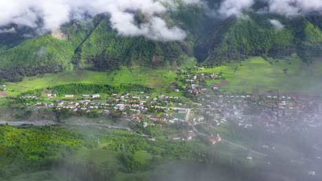 aerial: mestia highland town, view through clouds in caucasus mountains, georgia