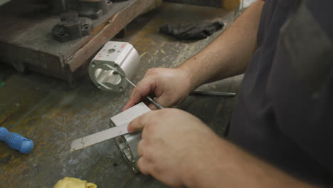 Caucasian-male-hands-factory-worker-at-a-factory-sitting-at-a-workbench-and-working-on-a-metal