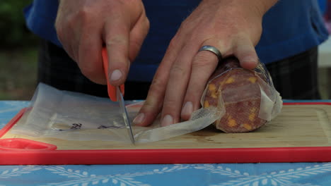 paquete de salami de queso entero y cuchillo en una tabla de cortar