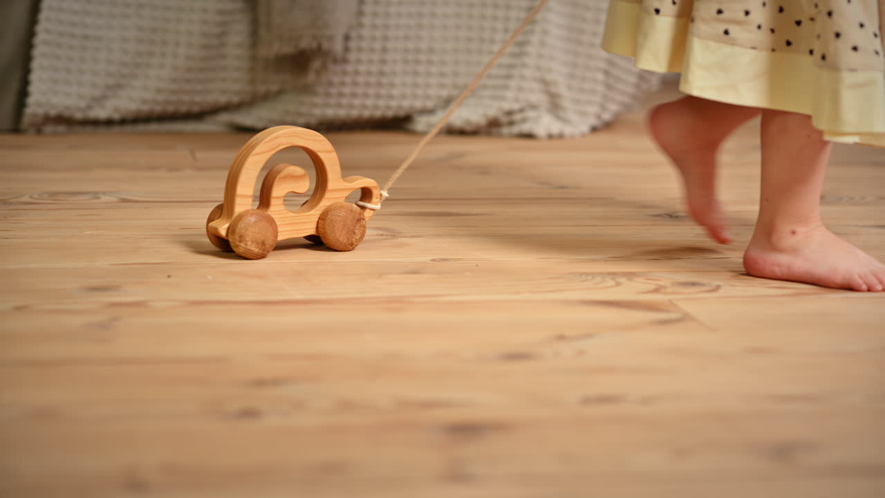 Little girl playing with a wooden snail rolling toy on the floor. Ecological and sustainability concept