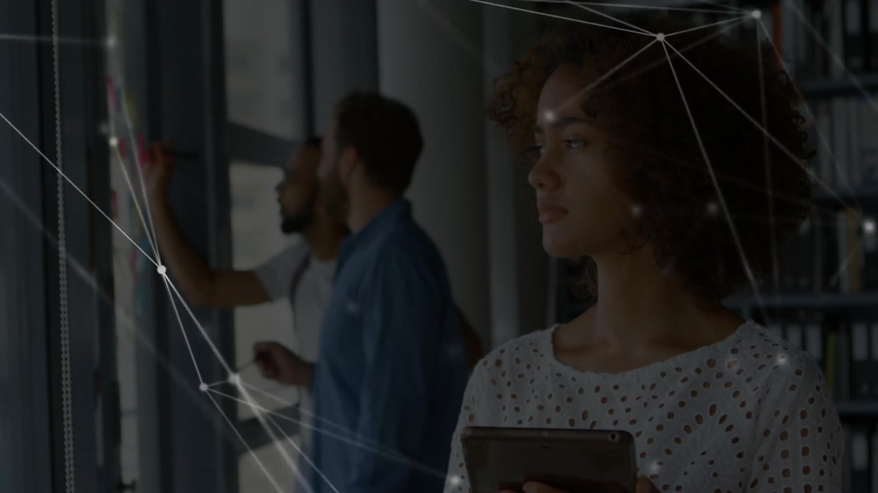 woman consulting tablet causing digital overlay for business while man placing notes on glass wall