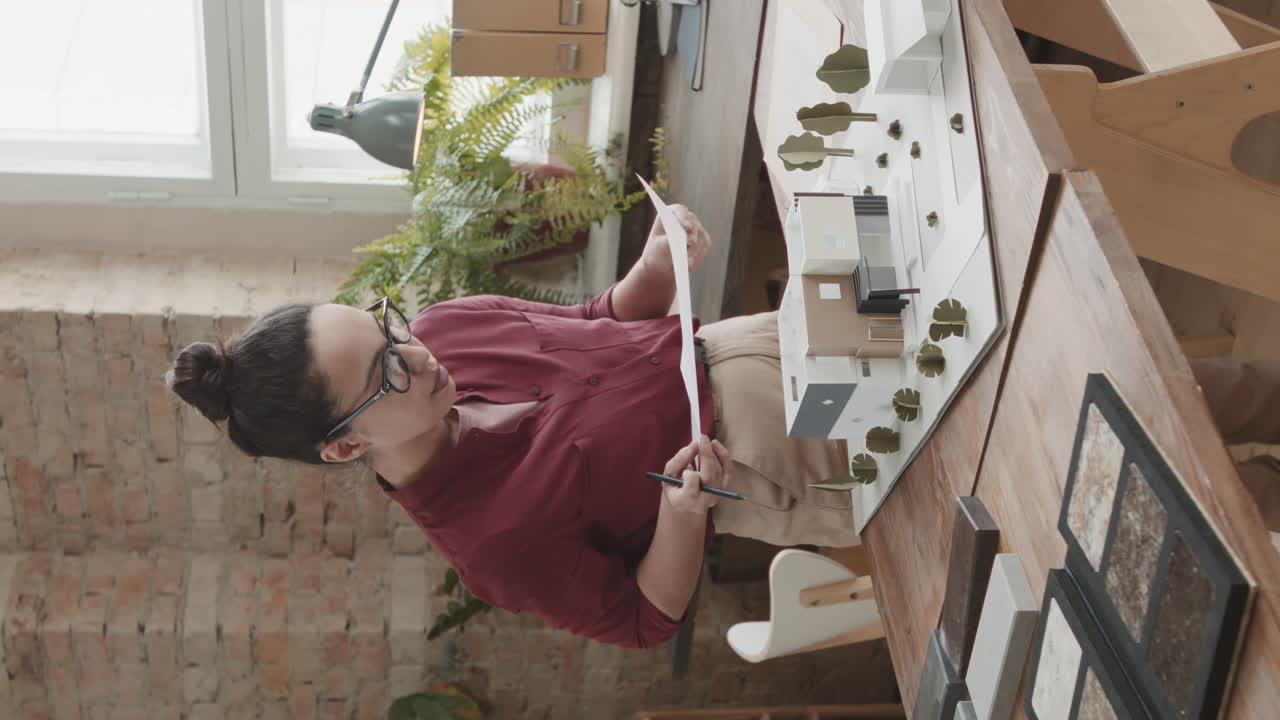 Female Architect Working On House Design Looking At 3D Layout