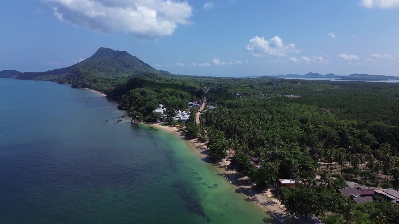 Ripresa aerea con drone che si alza rivelando la lunga spiaggia remota di Koh Jum, Thailandia, caratterizzata da acqua turchese cristallina e una costa tropicale incontaminata e deserta con una giungla fitta, che creano un paesaggio insulare pacifico.