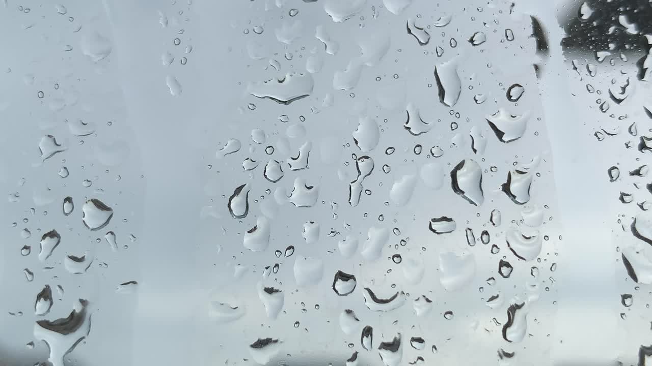 Rain drops on window from dark cold storm during the day