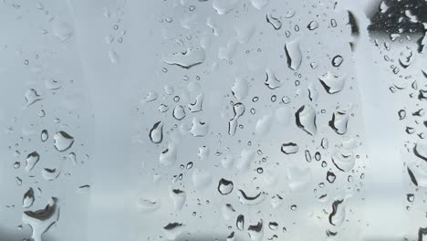 rain drops on window from dark cold storm during the day