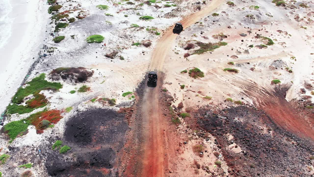 siguiendo dos buggies que conducen a través de tierras volcánicas desérticas vacías en una pista fuera de la carretera bajo el sol del mediodía