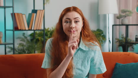Redhead-young-woman-presses-finger-to-lips-makes-silence-hush-sign-do-not-tells-gossip-secret,-quiet
