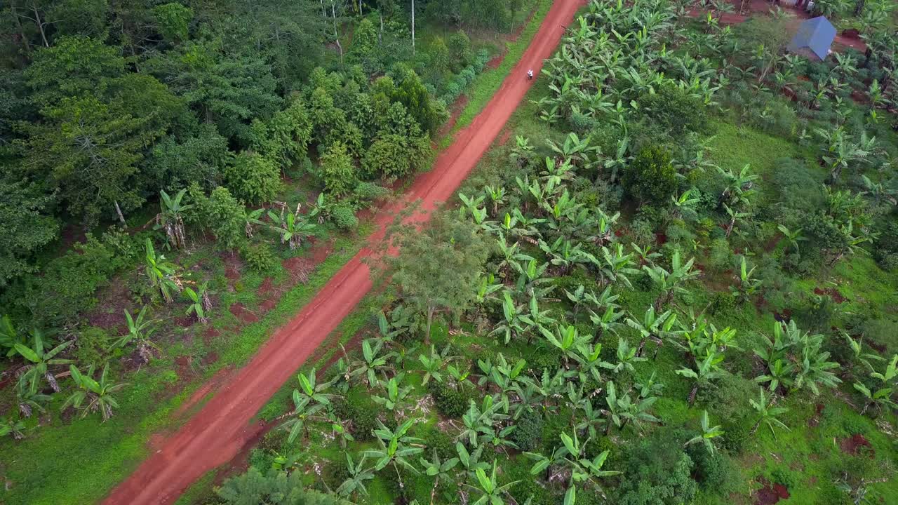 View Of A Cyclist On A Dirt Road In Mukono, Uganda - Drone Shot