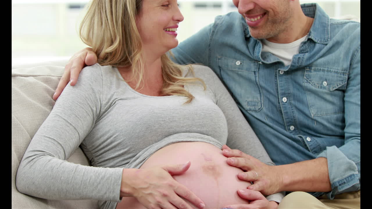 Donna incinta con il marito seduti sul divano