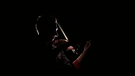 young handsome man plays electric violin on black background, isolated