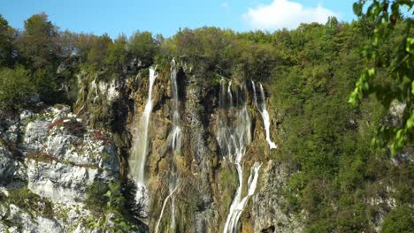 view of the tall, thin waterfalls of veliki slap with branches in the foreground in plitvice lakes national park in croatia, europe